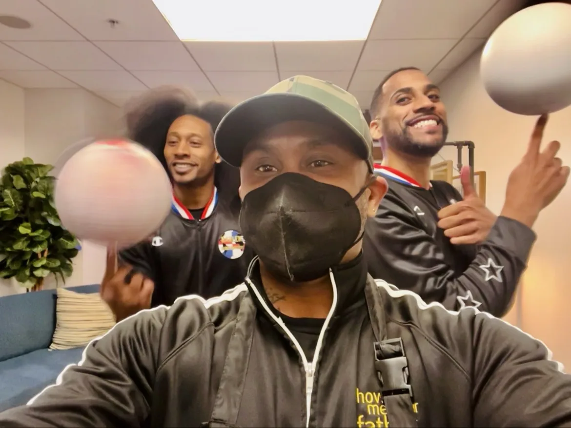 Two Harlem Globetrotters players spinning basketballs on their fingers in the green room