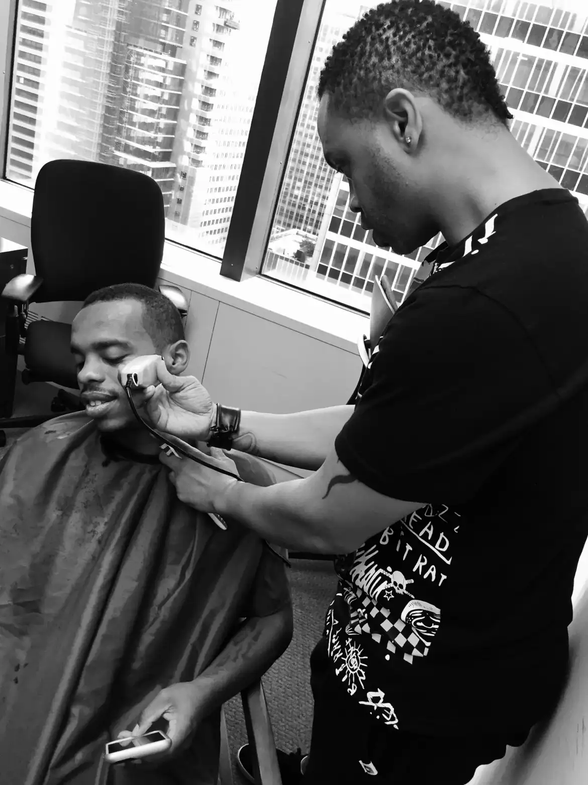 Black-and-white photograph of an edge-up in progress in front of high-rise windows