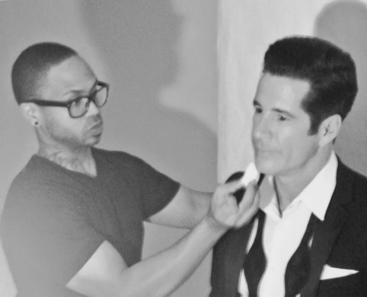 Black-and-white photograph of a client in a suit being groomed